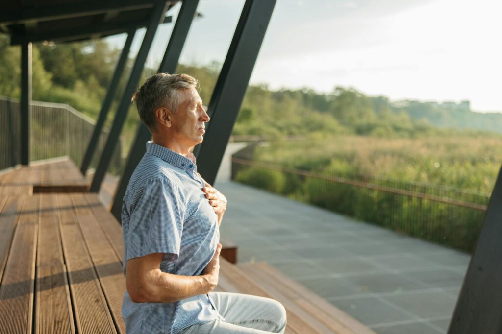 Senior man practicing meditation outdoors, embracing peaceful relaxation and mindfulness during daylight hours.