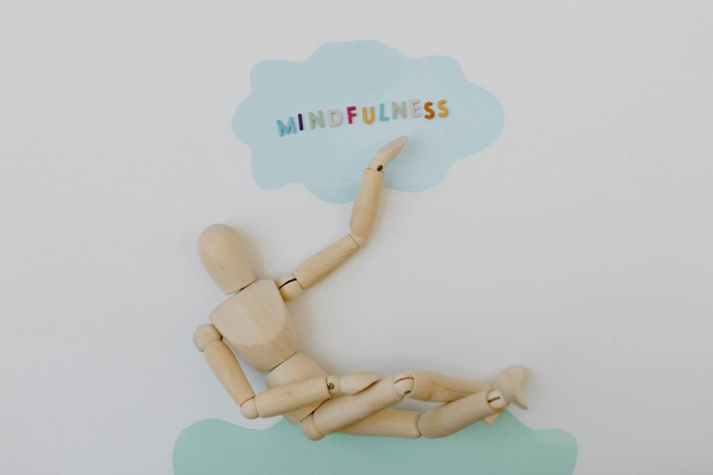 Wooden mannequin depicting mindfulness concept against pastel background.