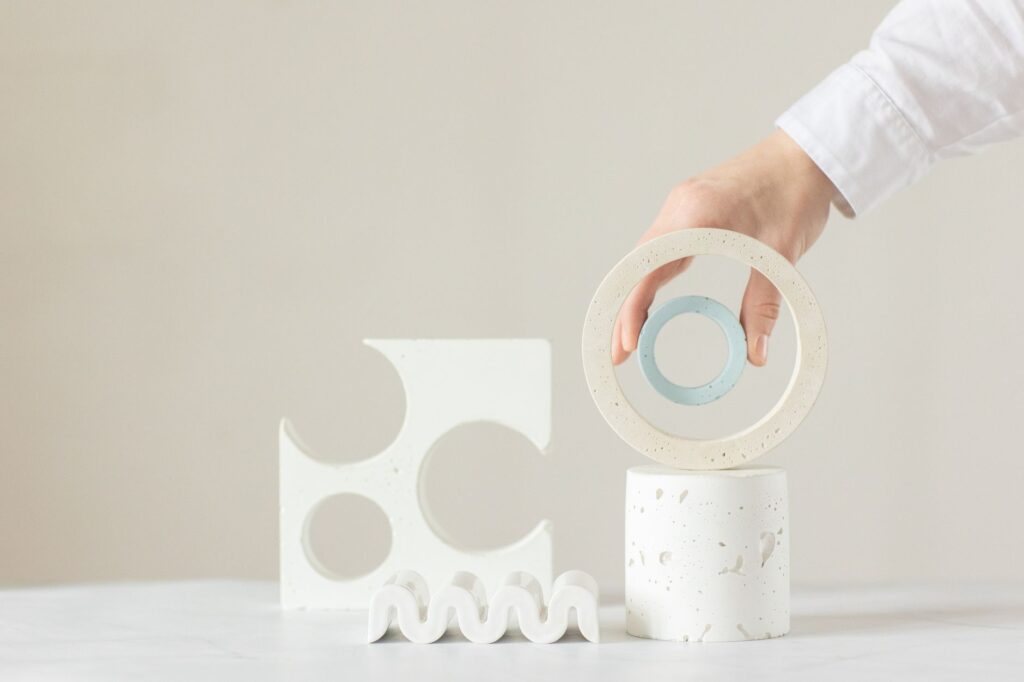 A hand arranging minimalist geometric shapes in a bright indoor setting.