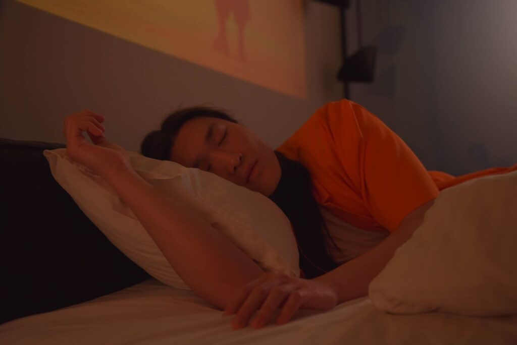 How Can I Manage Schizophrenia-Related Auditory Hallucinations in Daily Life? 1 A sleeping Asian man in a bed, enveloped in a moody atmosphere with soft lighting.